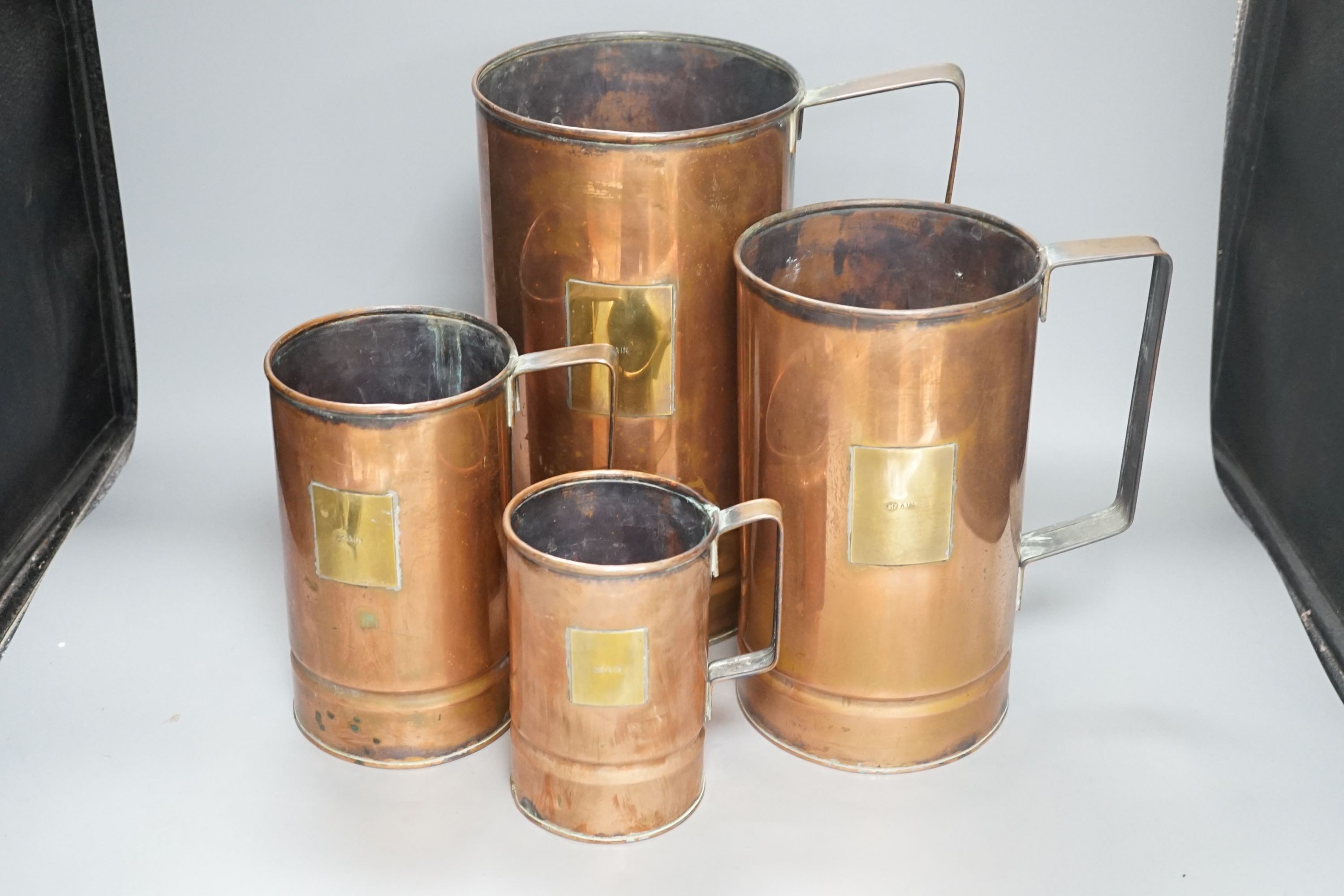 A graduated set of four copper and brass grain measures, tallest 39.5 cms high.